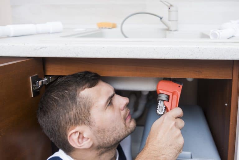Técnico trabajando con una llave en una instalación de agua de una cocina